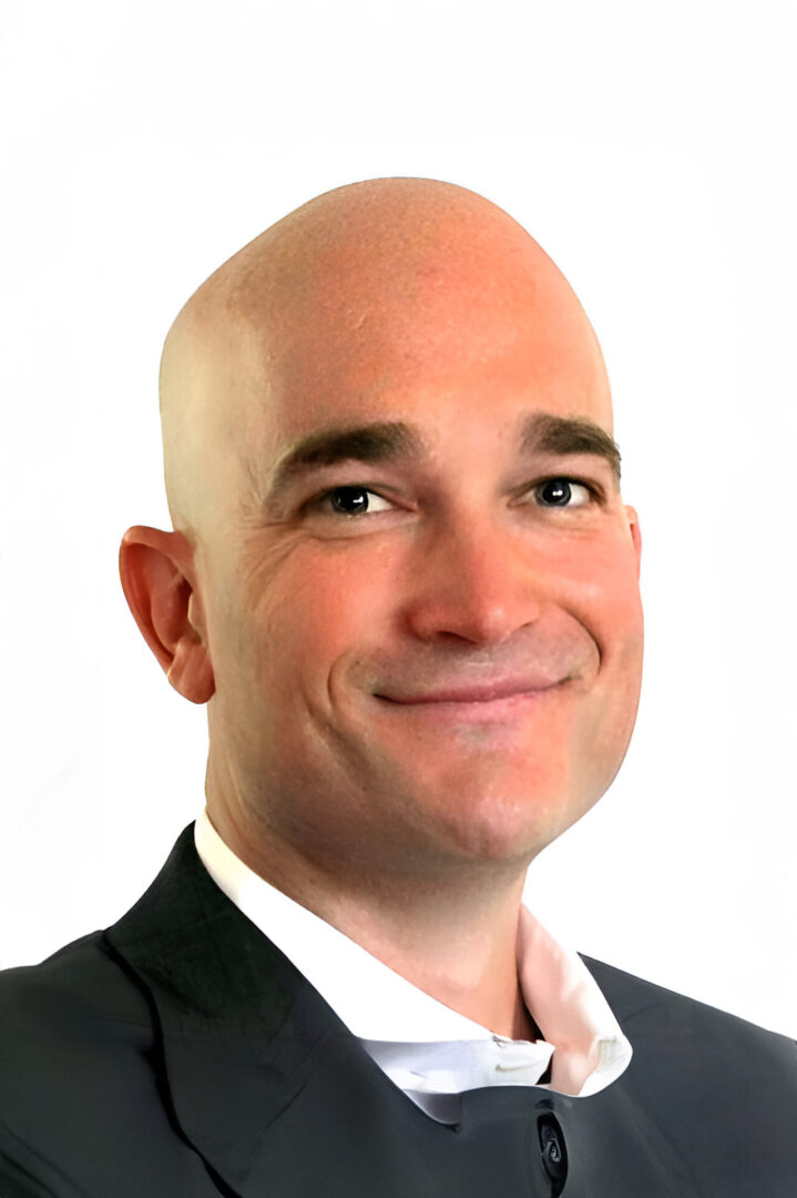 A bald man with a shaved head wearing a suit.