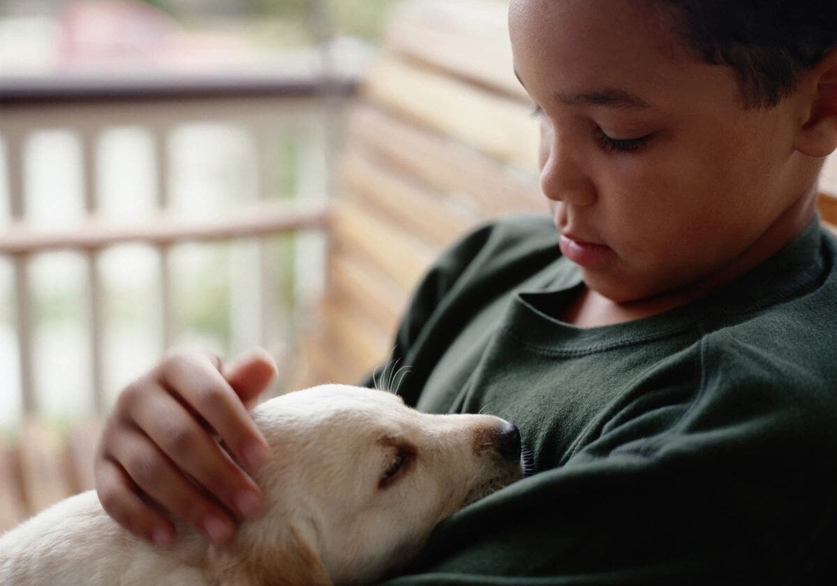 A boy holding onto his dog while he is sleeping.